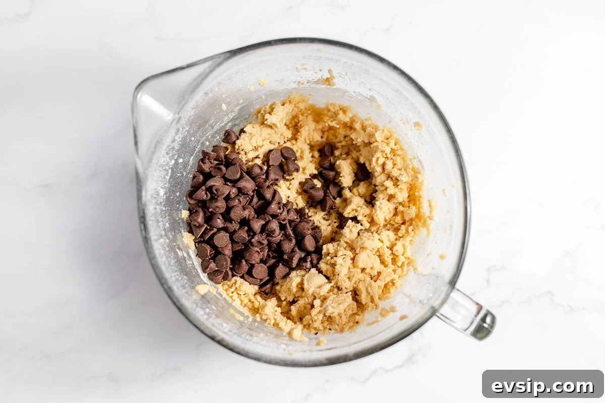 Chocolate chips added to the cookie batter in bowl.