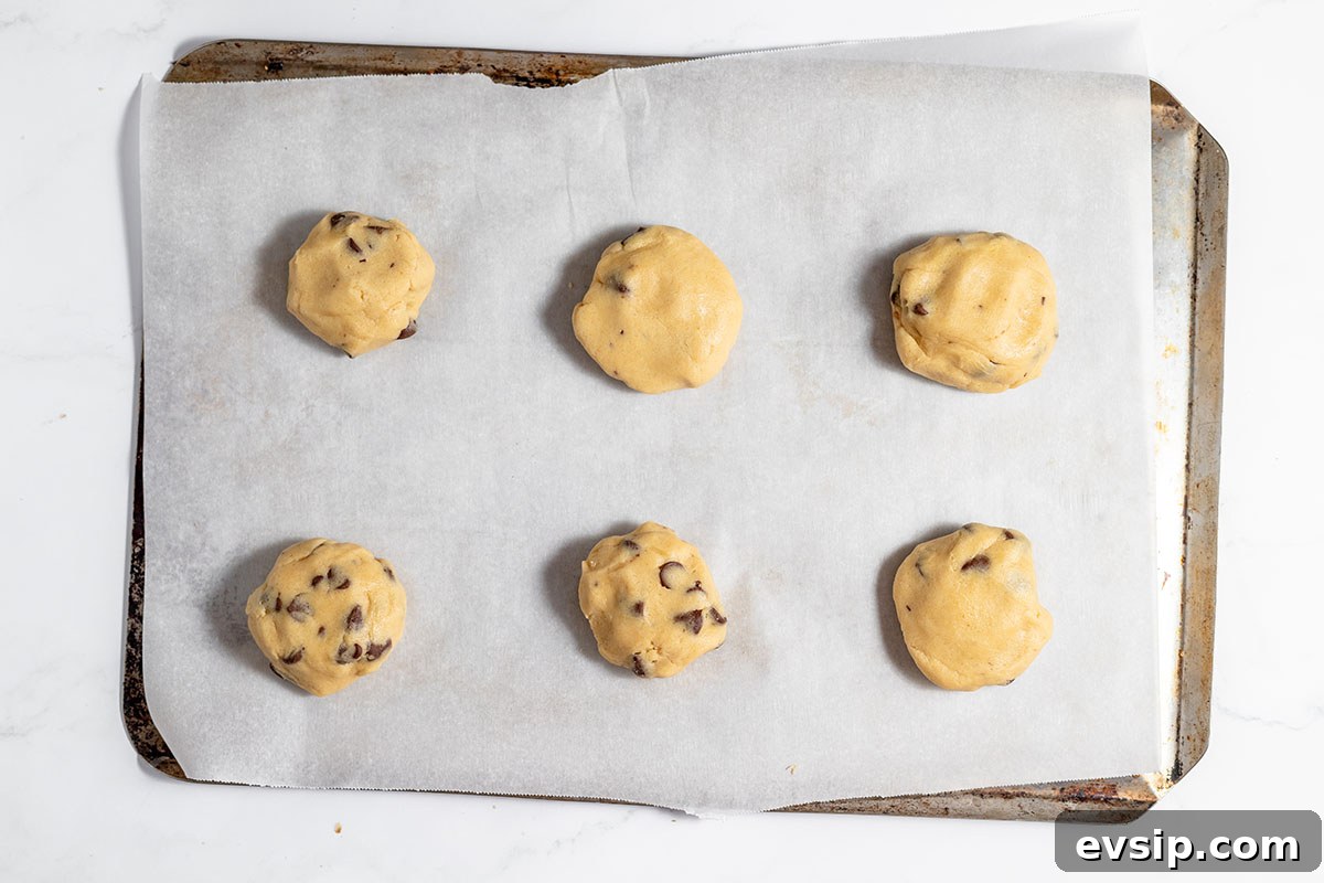 Caramel stuffed chocolate chip cookie dough on parchment-lined cookie sheet.