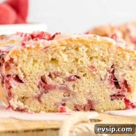 Cinnamon French Toast Roll-Ups with Maple Dipping Sauce 16 a loaf of strawberry bread with strawberries and glaze on top with a slice cut off on a wooden board