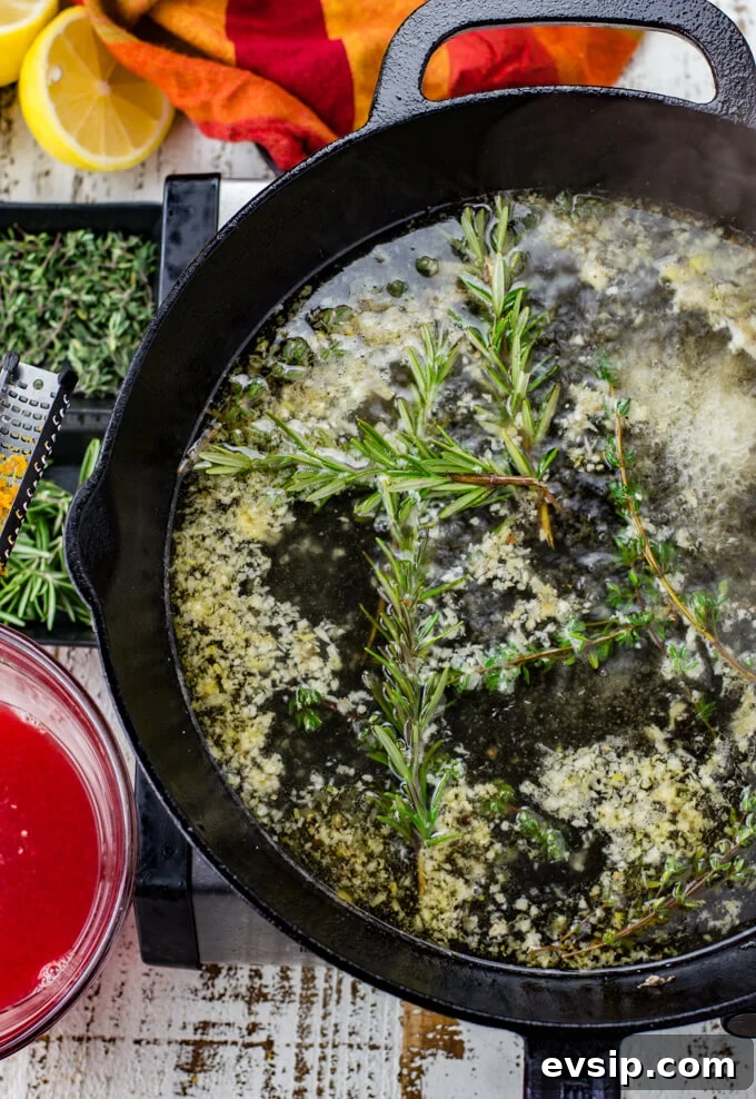 Cast Iron Seared Salmon in Blood Orange Sauce 8 Thyme, Rosemary and garlic simmers in white wine in a black cast iron skillet. A red and orange napkin, small bowls of thyme and rosemary and a bowl of blood orange juice sit next to the skillet.