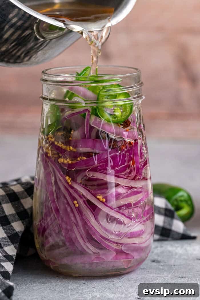 Pouring pickling vinegar over red onions in a jar