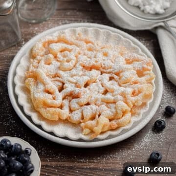 The funnel cake with pancake mix is on a plate with blueberries surrounding it.