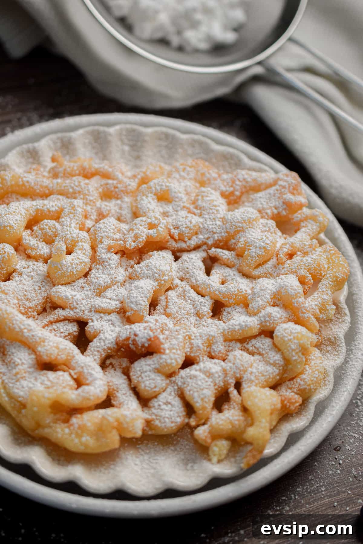Funnel Cakes Made with Pancake Mix: Simple Fair-Style Recipe 9 The funnel cake with pancake mix is on a double plate topped with powdered sugar.
