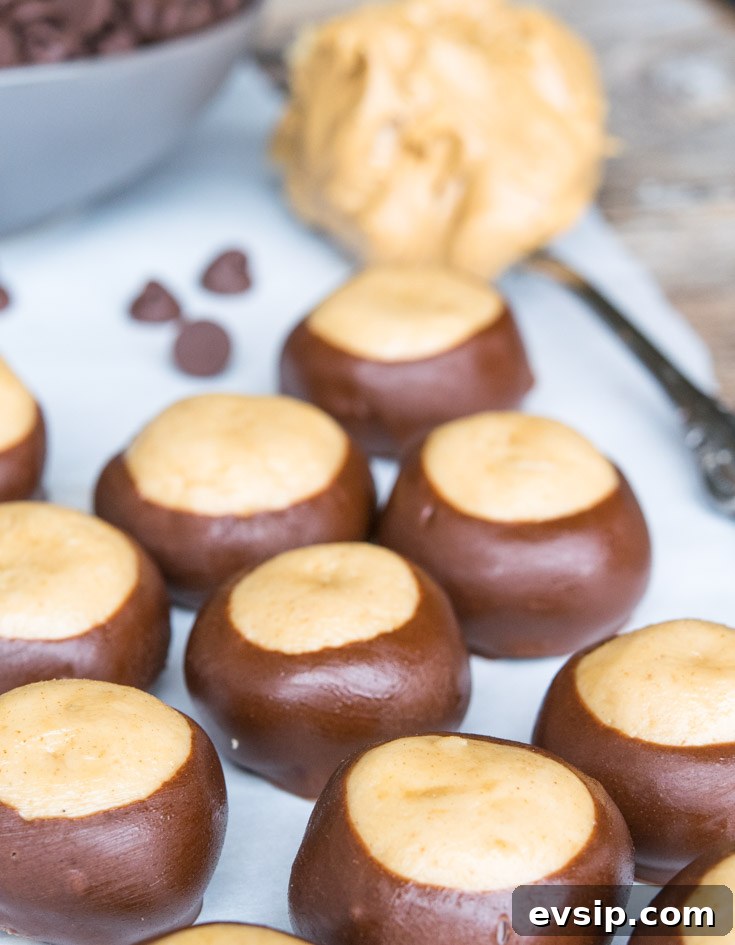 Our Classic Buckeye Recipe Is The Perfect Combination Candy, Creamy Peanut Butter And Luscious Chocolate. Homemade, Easy To Make, And Amazing! Buckeye Recipe lined up on a baking sheet, with a spoonful of peanut butter at the side