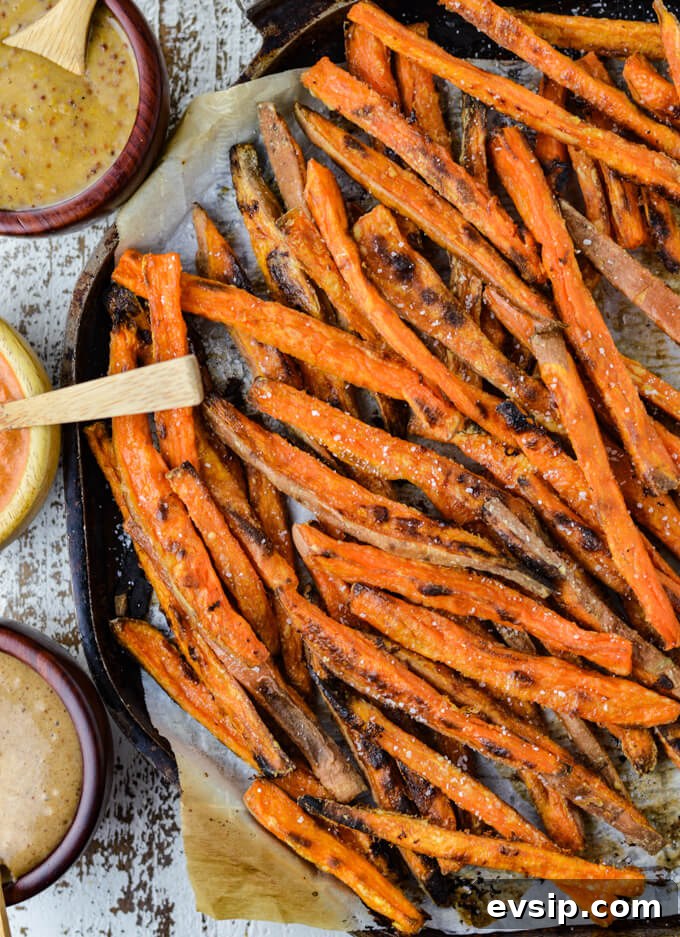 Baked Sweet Potato fries on a pan with 3 different dipping sauces.