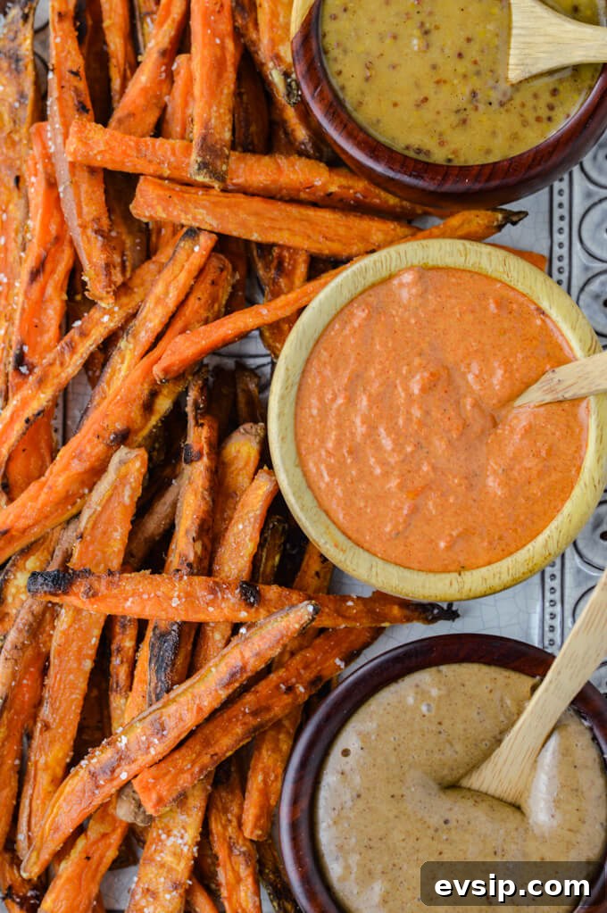 A platter of baked sweet potato dries sit next to three bowls of dipping sauces.