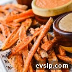 A platter of baked sweet potato fries with 3 bowls of dipping sauce sits next to them.