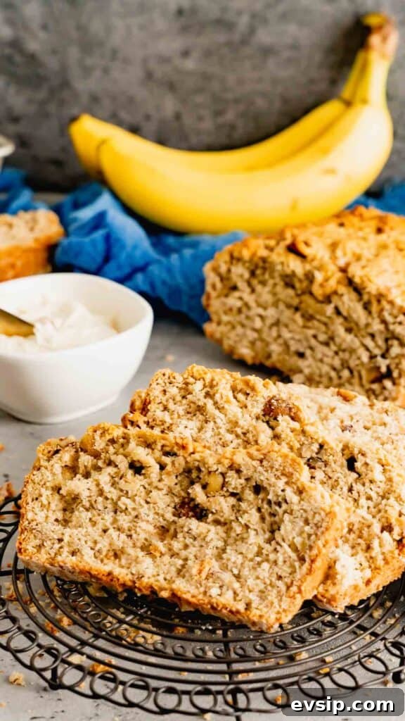 Betty White's Banana Bread sliced on a cooling rack with bananas in the background. 
