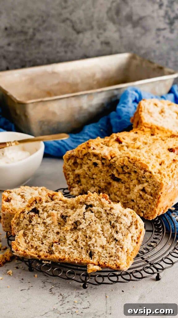 Sliced banana nut bread with the loaf pan in the background. 