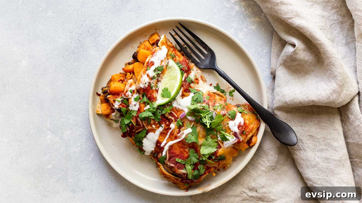 Sweet Potato Enchilada Casserole Recipe 5 Two sweet potato enchiladas on a plate with a fork and napkin.