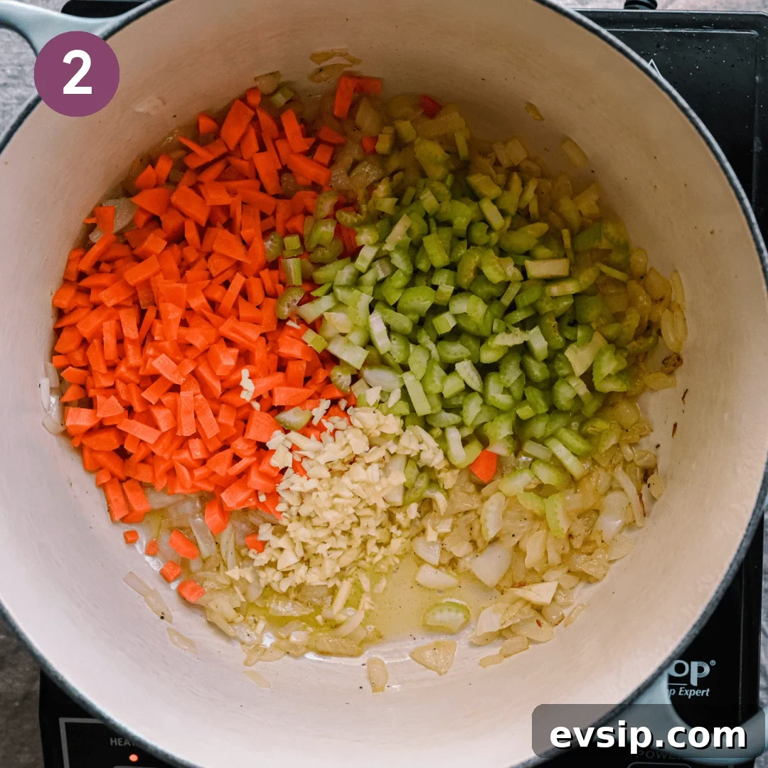 diced carrots and celery sitting on top of sauteed golden onions in a dutch oven. 