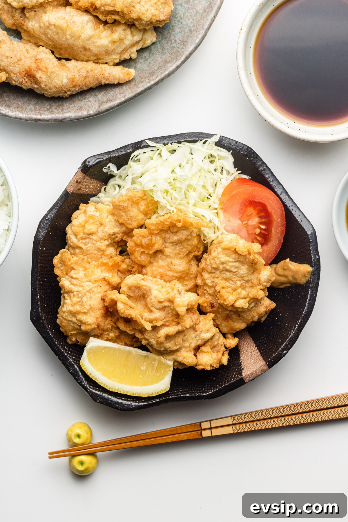 chicken tempura with cabbage, tomatoes and lemon on a black plate