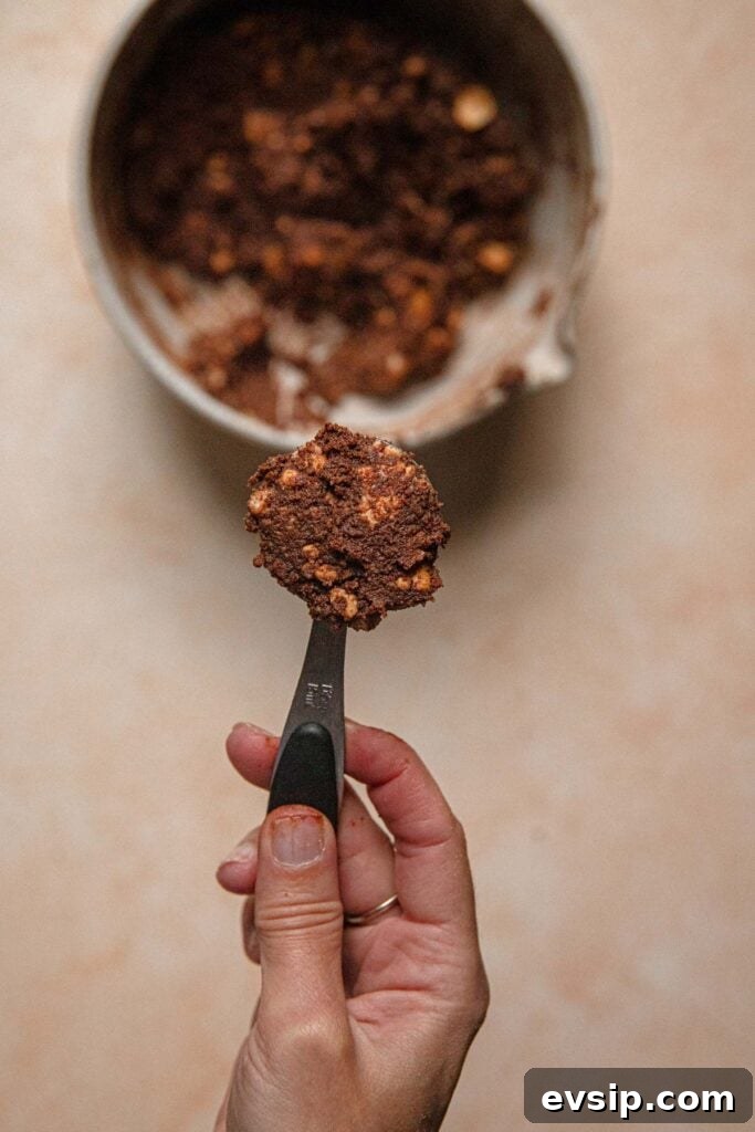 Israeli Chocolate Truffles Recipe — Classic No-Bake Treat 6 A hand holding a tablespoon with cookie dough.