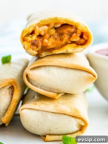 A stack of three cooked burritos and the top one has a bite out of it.