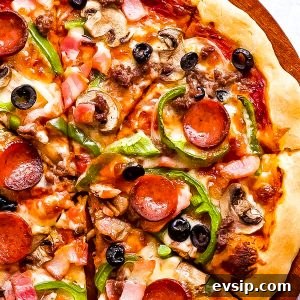 a pizza with pepperoni, peppers, olives and cheese on top.