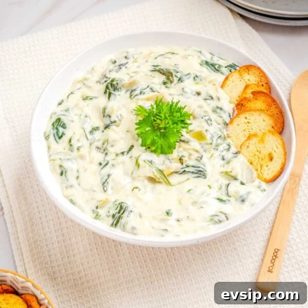 Overhead view of the spinach artichoke dip in a white bowl.