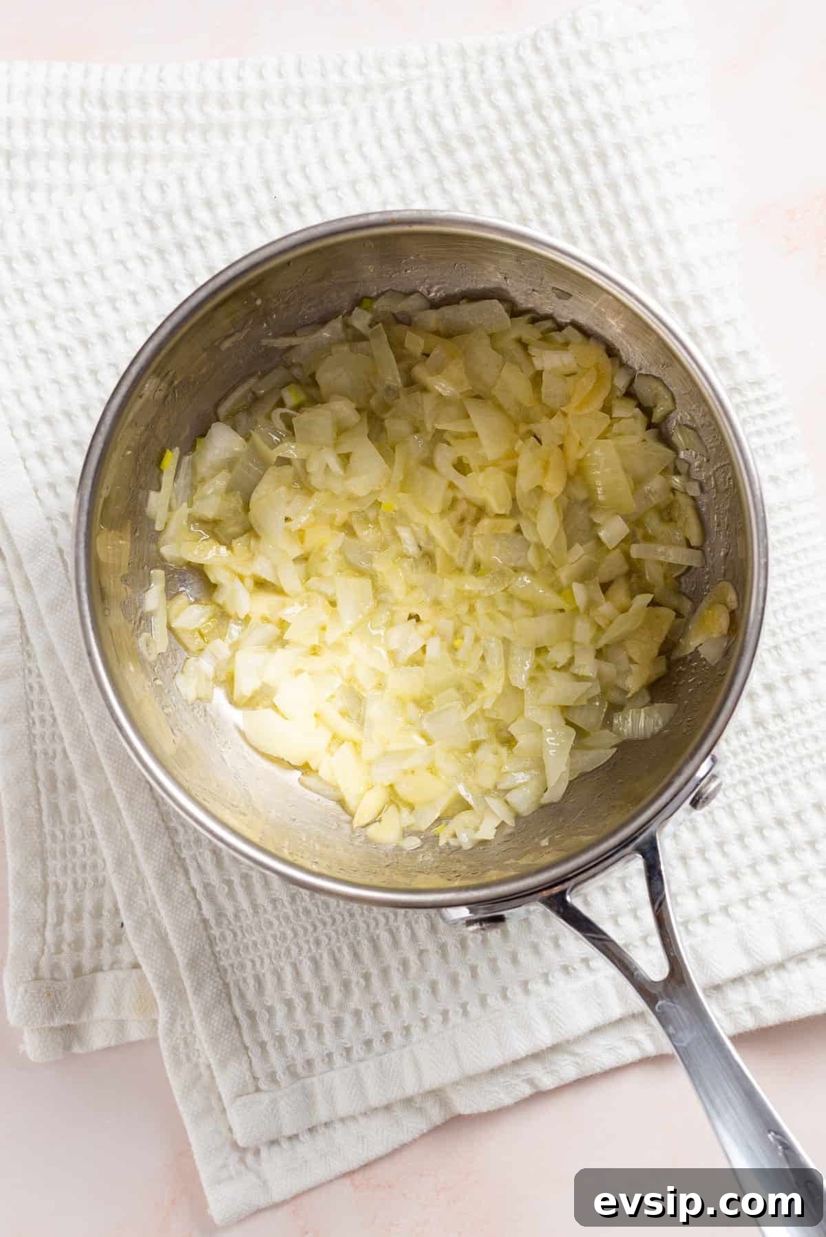 An image of onion, garlic, and jalapenos sauteed in melted butter in a saucepan.