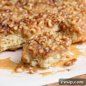 Gluten-Free Dairy-Free Banana Monkey Bread Recipe 4 A close-up of Gluten and Dairy Free Banana Bread Monkey Bread sits on parchment paper, with one piece pulled away, showing its soft, fluffy texture and sticky, syrupy topping of chopped nuts and caramel sauce.