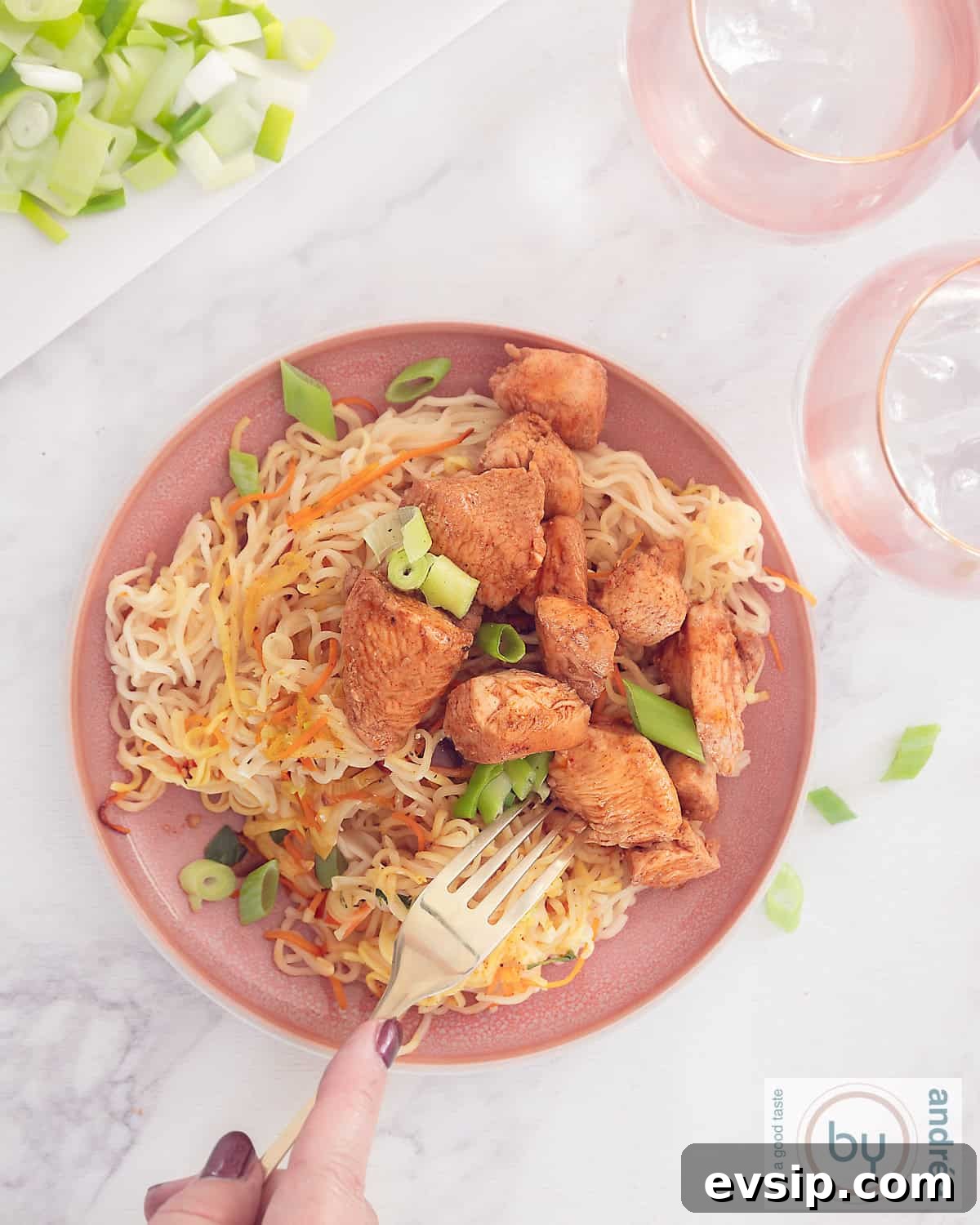 A photo from above of a pink plate with noodles, vegetables and diced chicken Cantonese style without packets and bags.