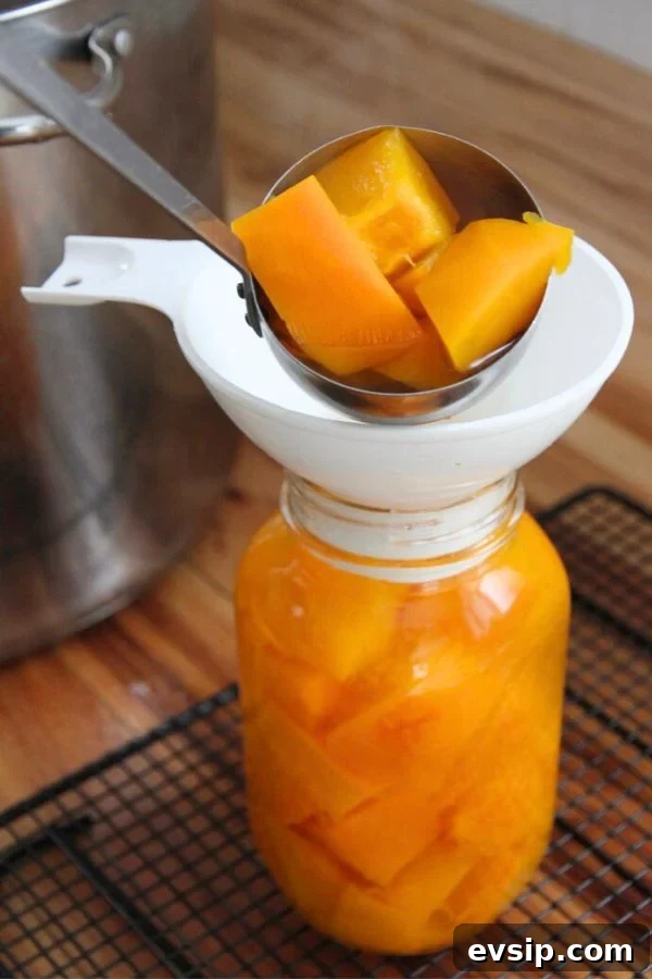 Ladling hot pumpkin and boiling water into a quart jar.