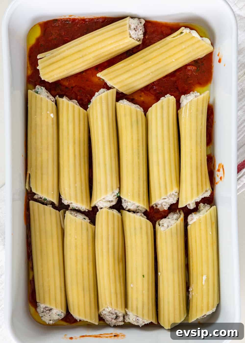 Cheesy Beef Manicotti Recipe with Homemade Marinara 5 overhead process shot: stuffed manicotti over sauce in a baking dish before baking