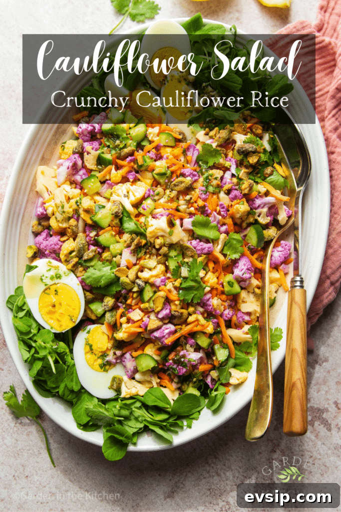Cauliflower salad in large white platter with serving utensils.