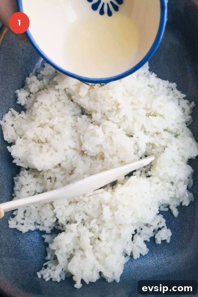 Mixing vinegar through sushi rice in a dish.