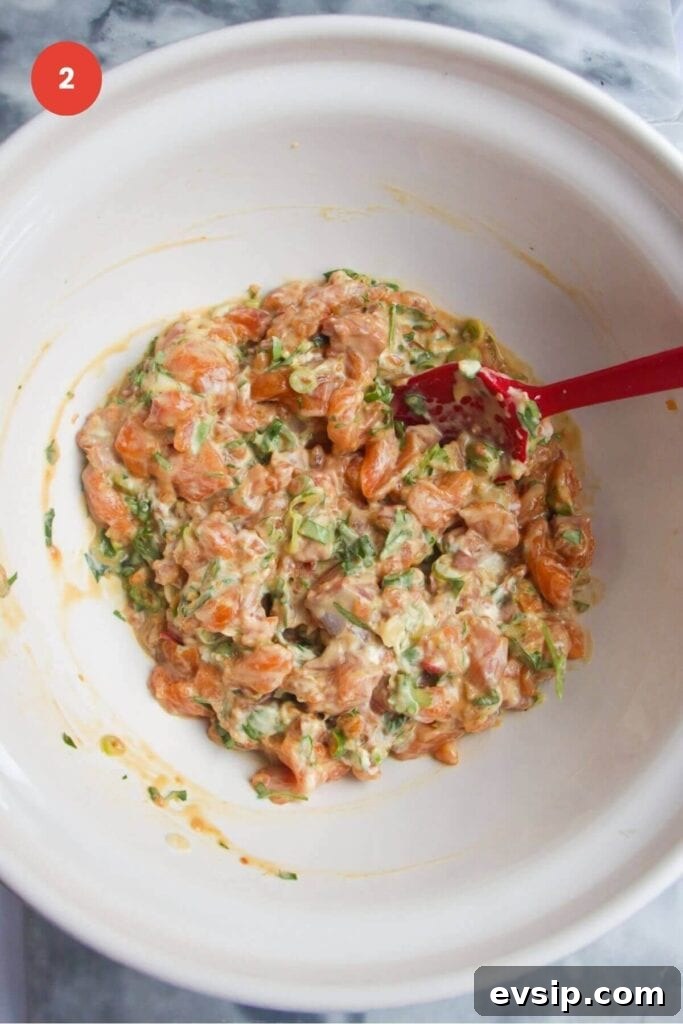 Salmon mixed with seasoning in a large mixing bowl.