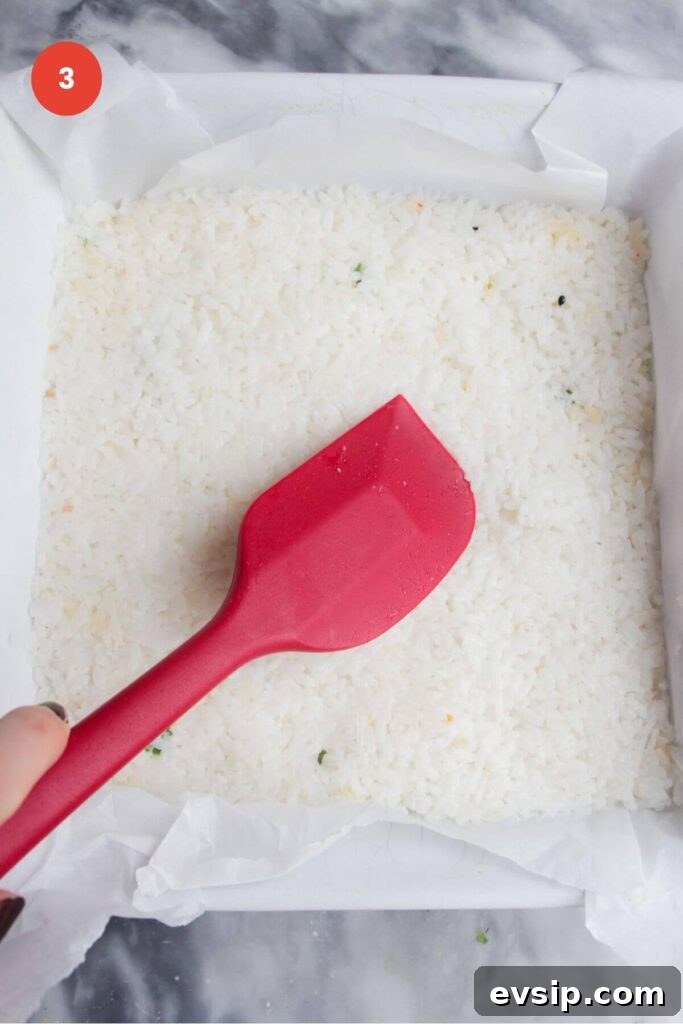 Spatula pressing rice into a baking dish.