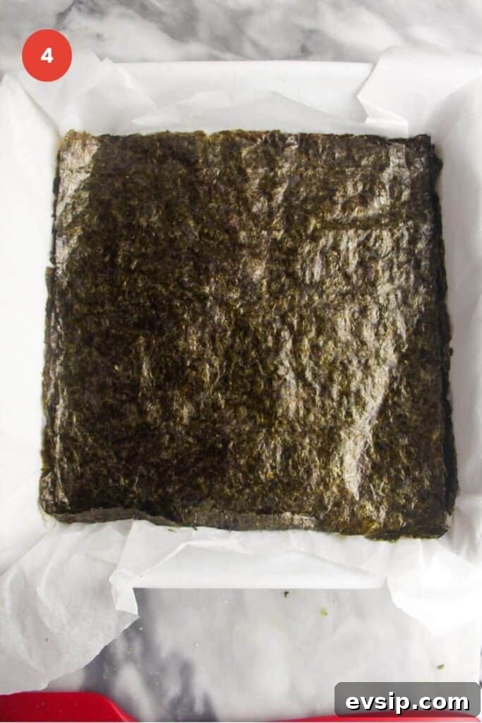 Nori sheet placed on top of rice in baking dish.