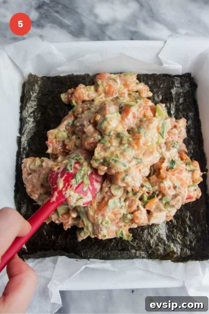 Salmon mixture piled on top of nori sheet in a baking dish.