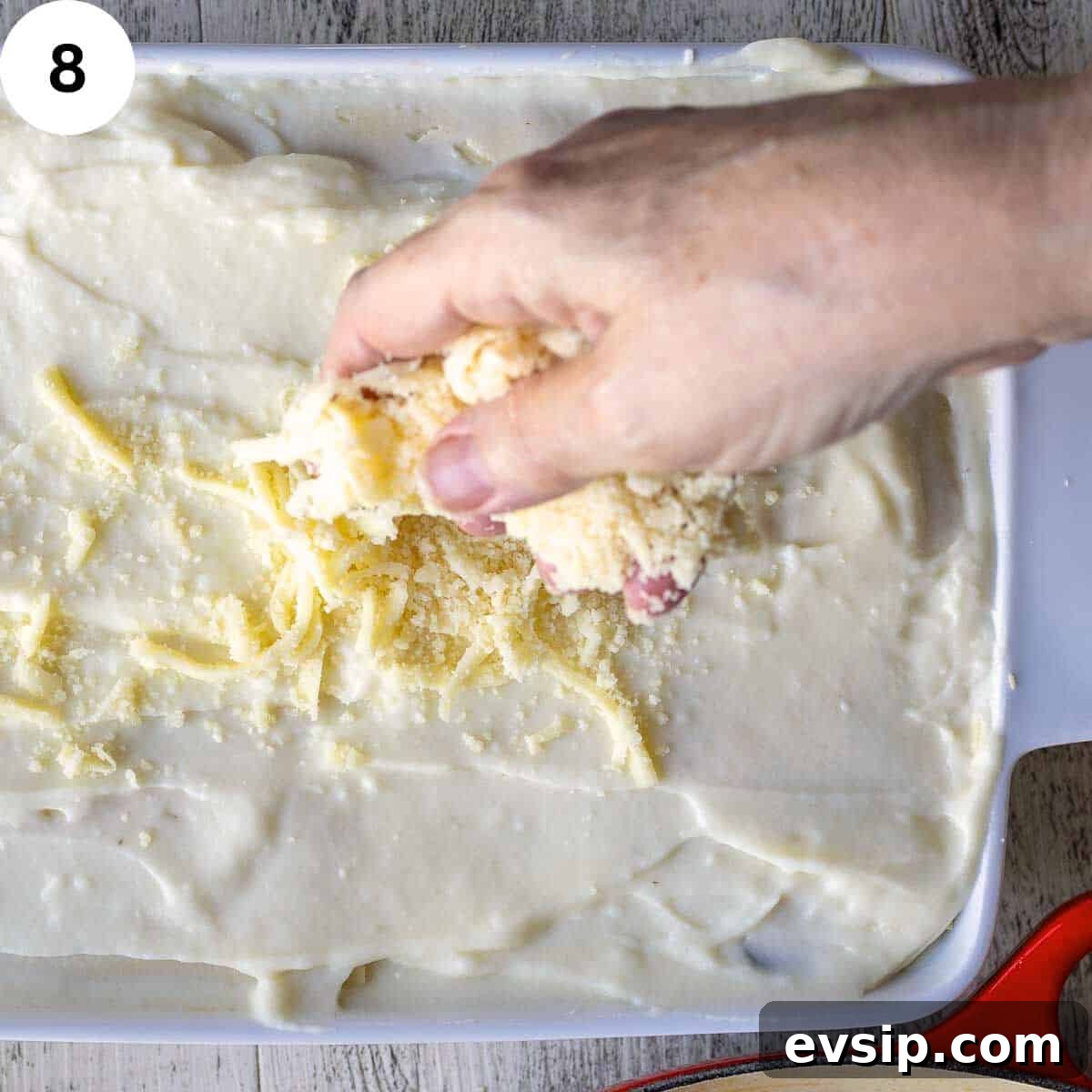 Topping uncooked lasagna with cheese before baking.