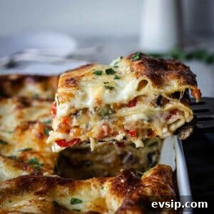 A slice of vegetable lasagna with white sauce being lifted out of a baking dish.