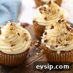Carrot Cake Cupcakes from Box Mix — Moist, Spiced & Quick 9 frosted carrot cake cupcakes topped with chopped nuts.