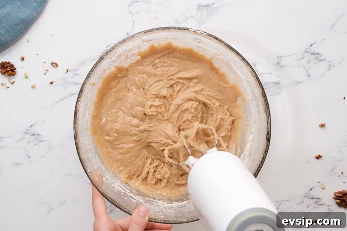 Carrot Cake Cupcakes from Box Mix — Moist, Spiced & Quick 10 beating spiced cupcake batter in a glass bowl with a hand mixer.
