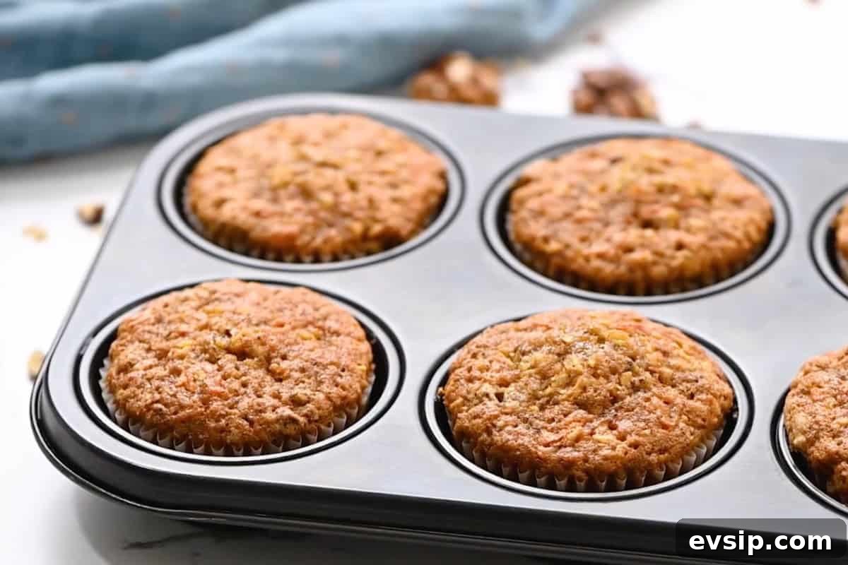 Carrot Cake Cupcakes from Box Mix — Moist, Spiced & Quick 12 baked carrot cake cupcakes in a cupcake tin.