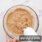 Carrot Cake Cupcakes from Box Mix — Moist, Spiced & Quick 5 beating spiced cupcake batter in a glass bowl with a hand mixer.