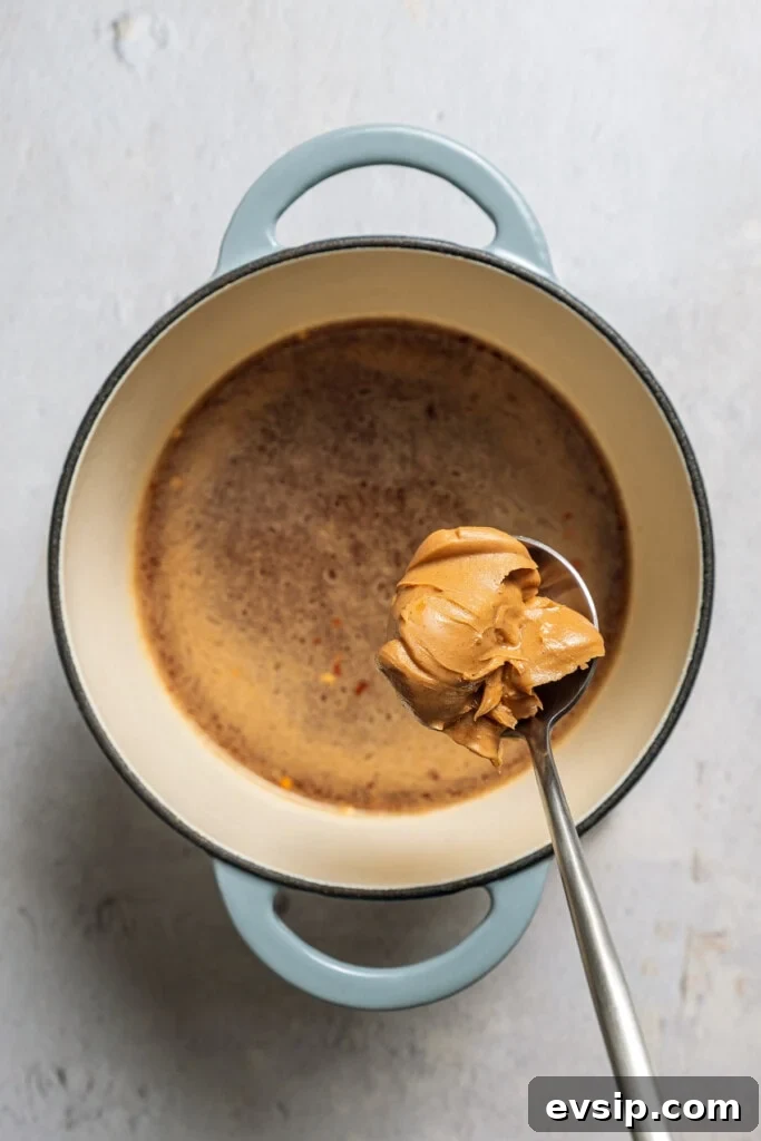 Adding peanut butter to hot chicken broth.