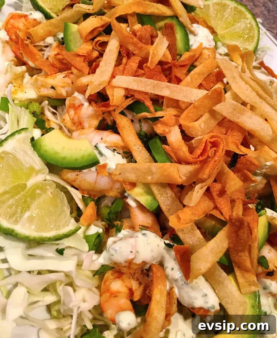 A taco salad made with shrimp, avocado, cabbage, lime and seasonings