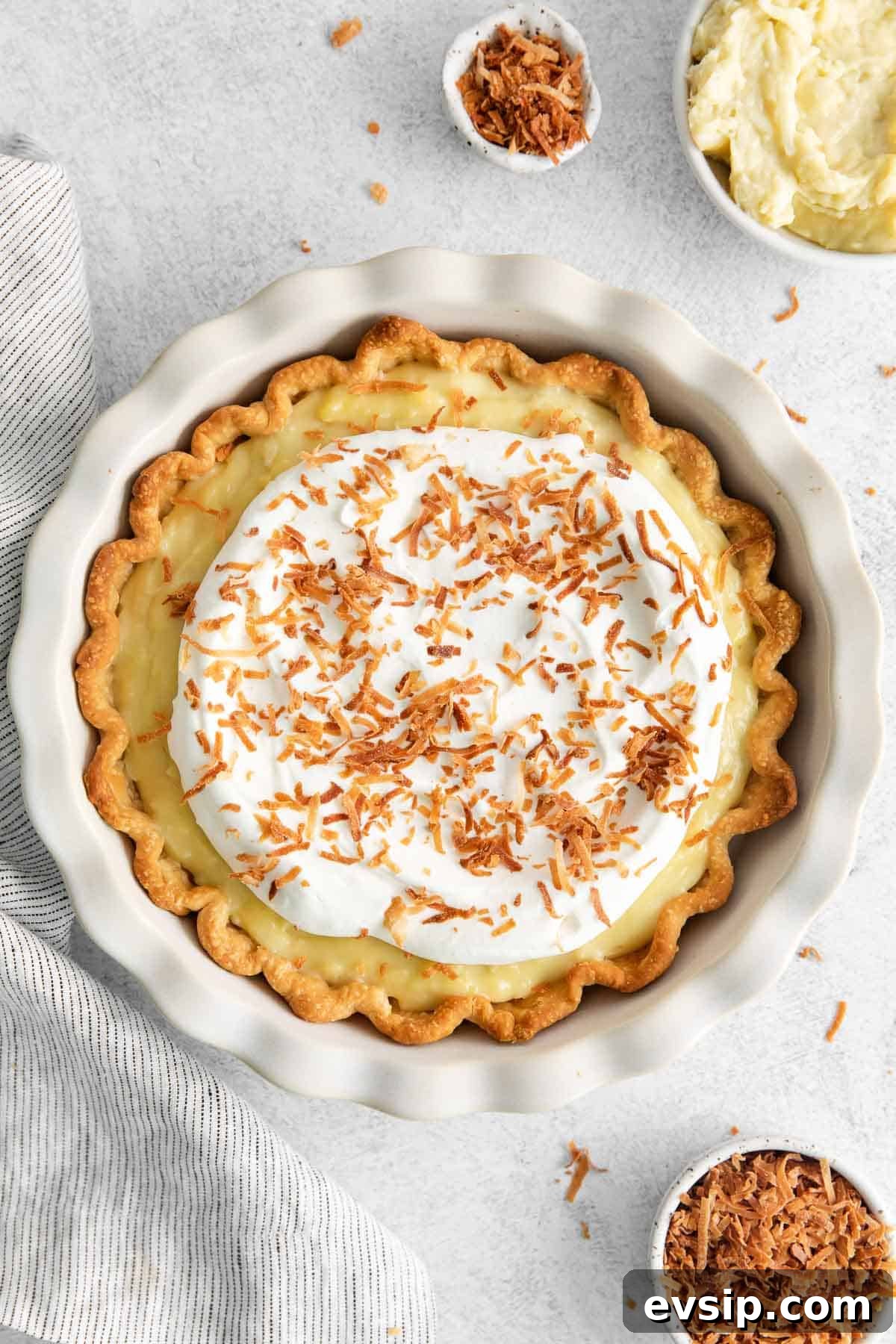 Dairy-free coconut cream pie surrounded by coconut shreds and cream in a bowl