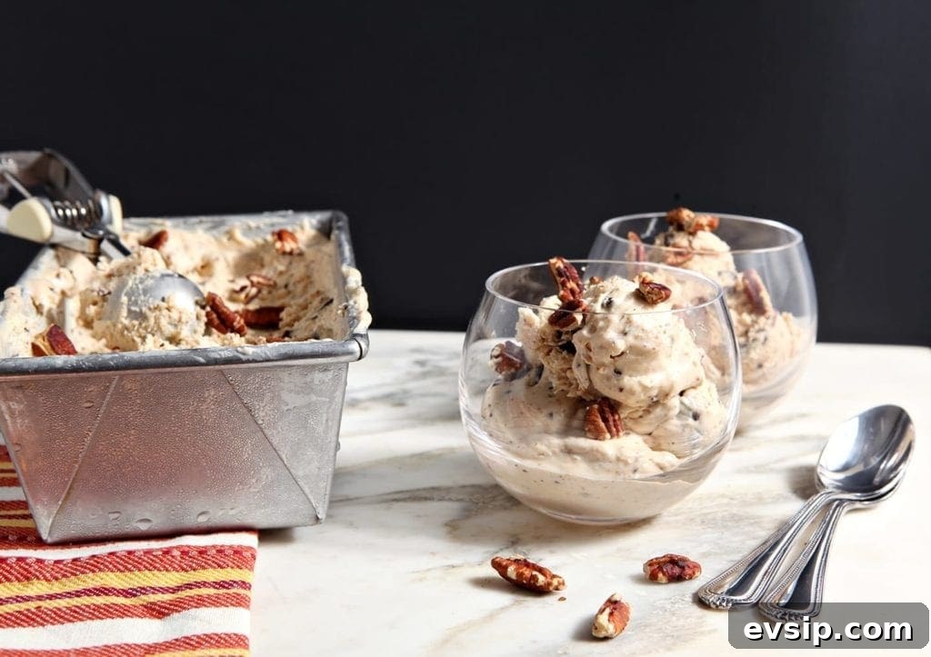 No churn ice cream scoops in cups on marble with pecans and spoons