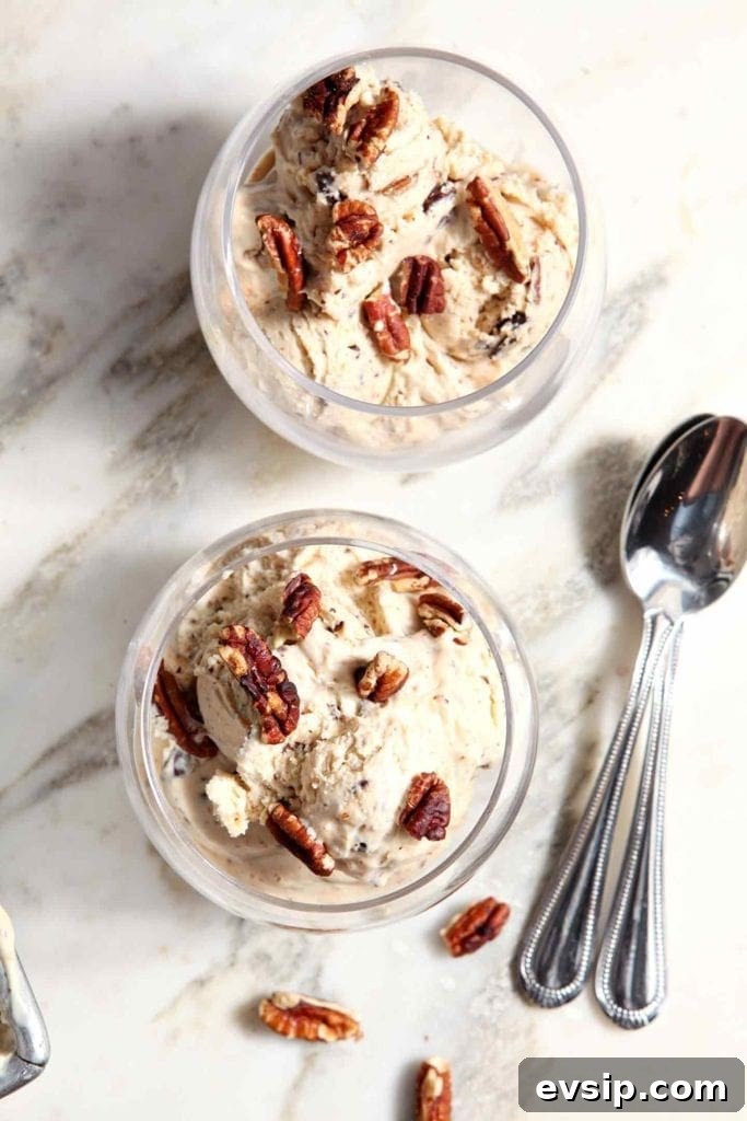 Two servings of No Churn Peanut Butter Pecan Chip Ice Cream in bowls with spoons on marble