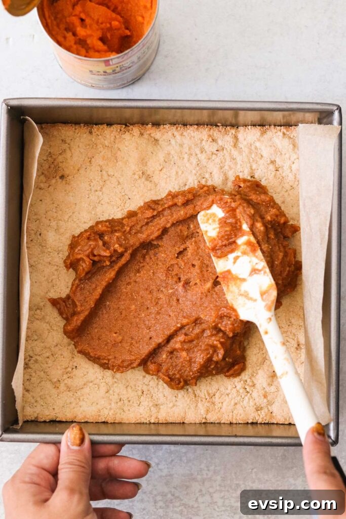 Spreading pumpkin peanut butter filling over the baked base layer