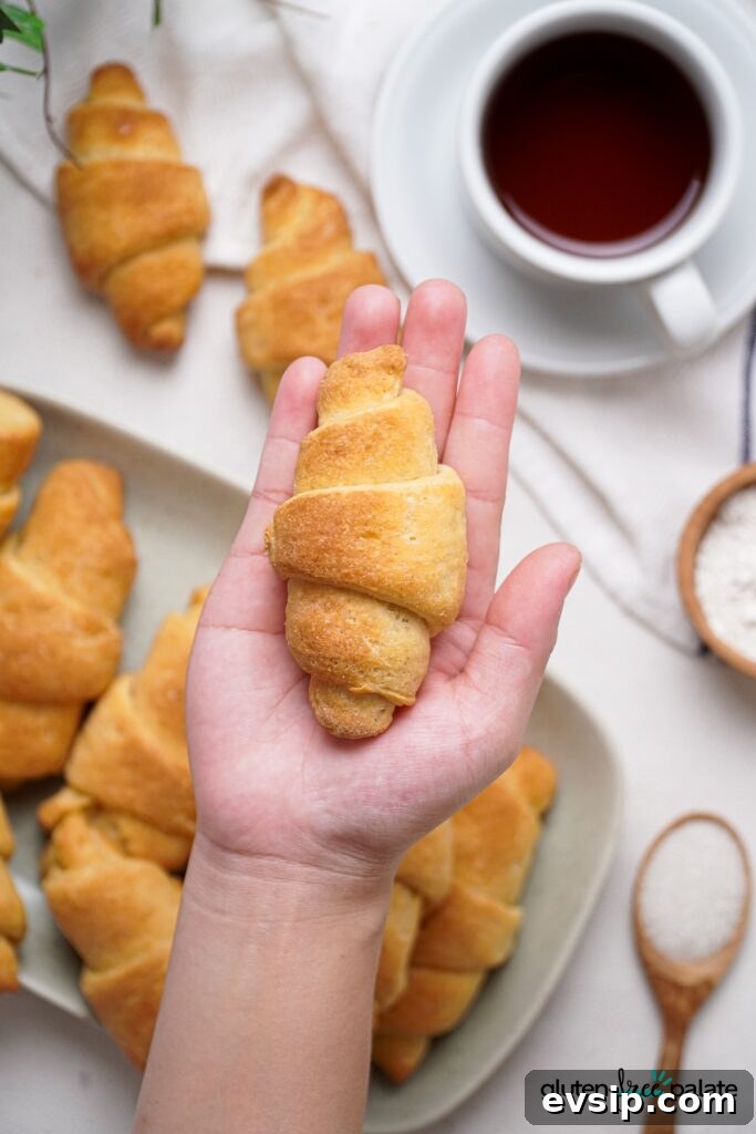 Irresistible Gluten-Free Brunch Recipes You’ll Crave Again 17 Gluten-Free Crescent rolls held in a hand with a cup of tea in the background. Use these to make breakfast sandwiches.