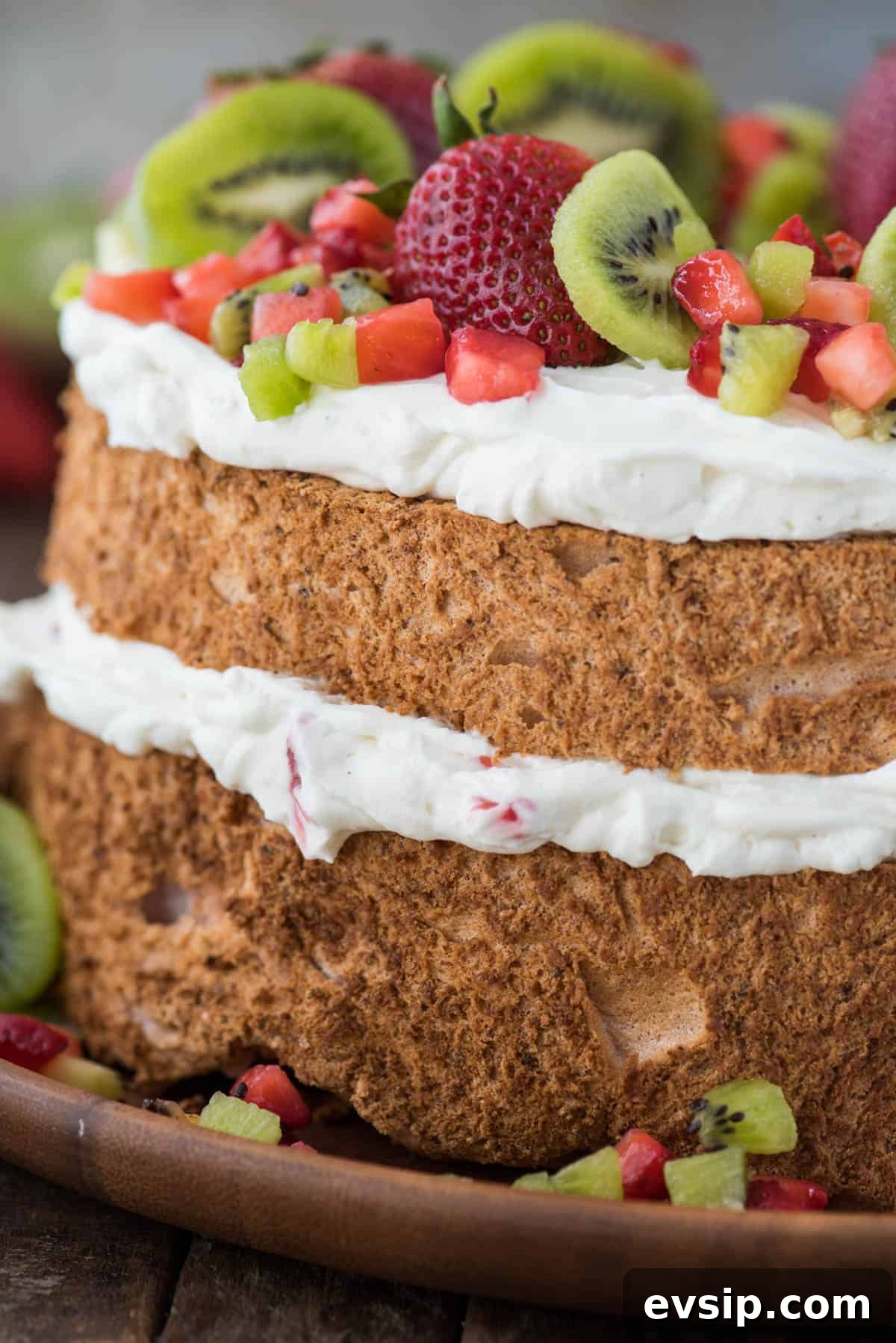 Light and Fluffy Strawberry Angel Food Cake Recipe 5 close up image of the side of strawberry angel food cake with whipping cream, strawberries and kiwi