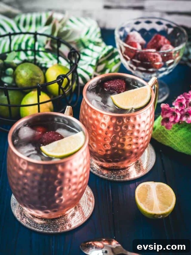 10 Moscow Mule Variations to Try Tonight 3 Gorgeous copper cups filled with delicious strawberry Moscow mule placed on blue wooden ground.