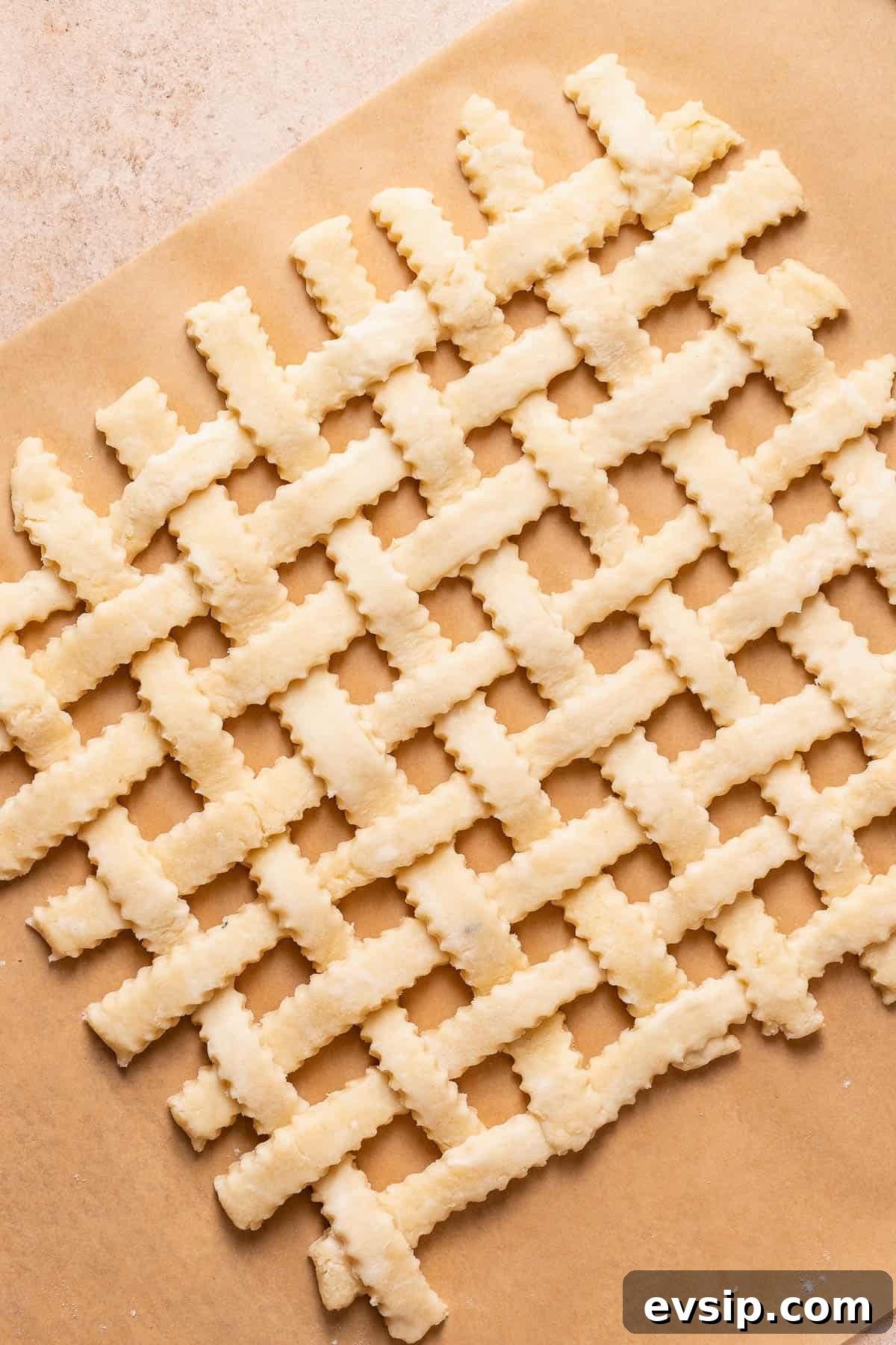 Pie crust strips arranged into a lattice top on parchment paper.