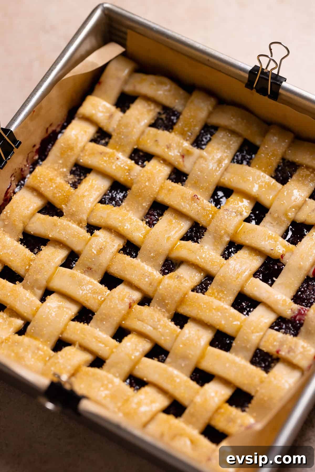 Blueberry bars with pie filling and lattice top in a baking pan before baking.