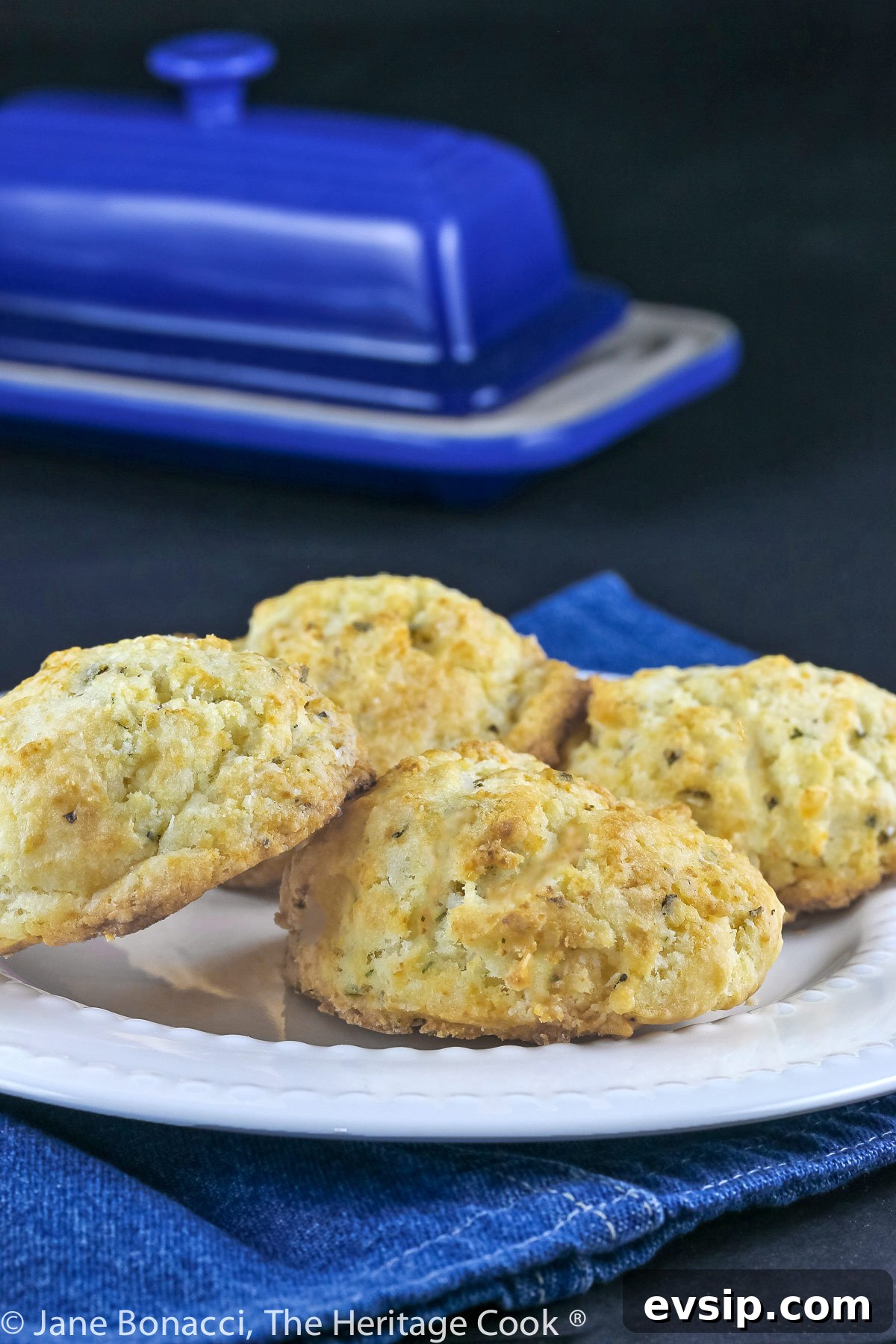 Biscuits on white plate with blue butter dish in background.