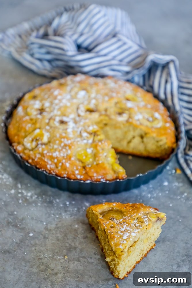 A slice of banana cake on a table next to a blue tablecloth, perfect for an easy and delicious apple banana bread recipe.
